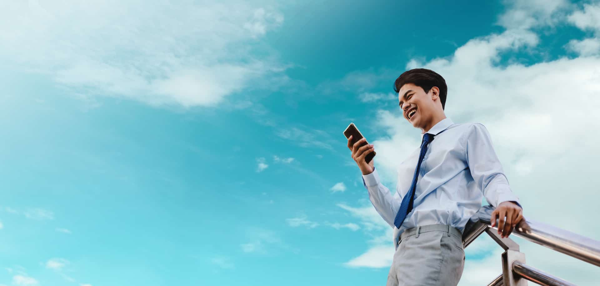 A smiling businessman uses a bulk SMS provider to send messages from his smartphone.